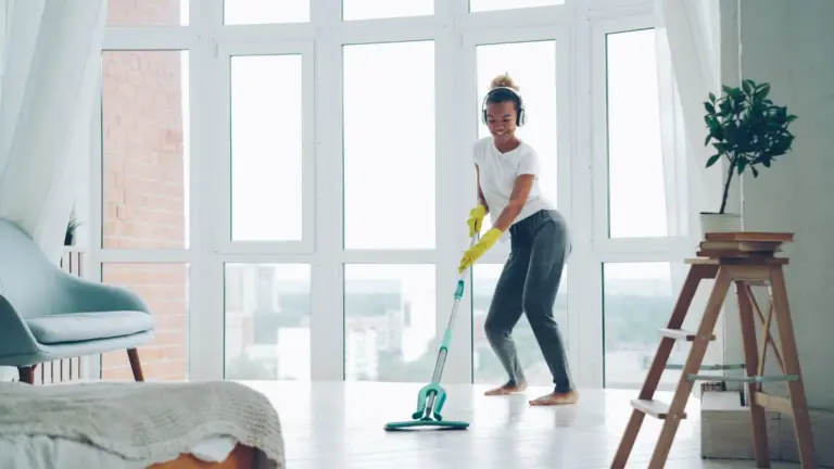 Smiling woman mopping a bright, sunlit room