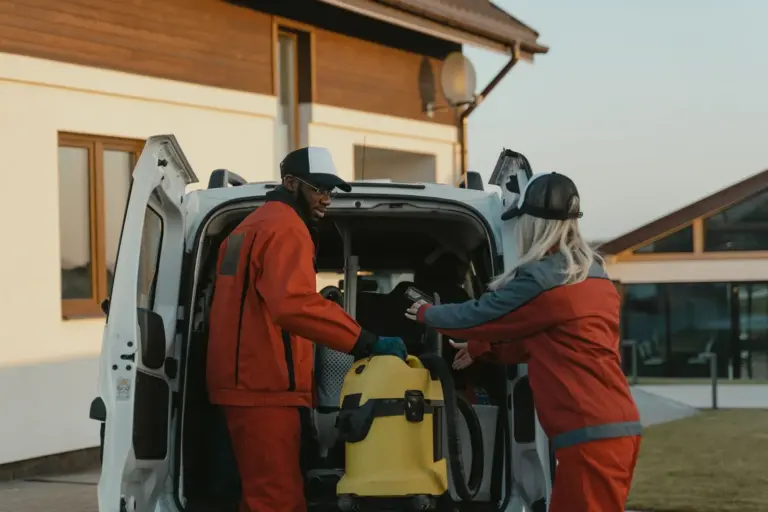 Cleaning crew unloading equipment from a van outside a house