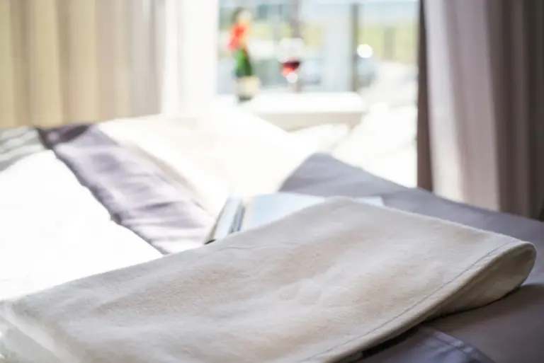 Fresh white towel laid on a made bed