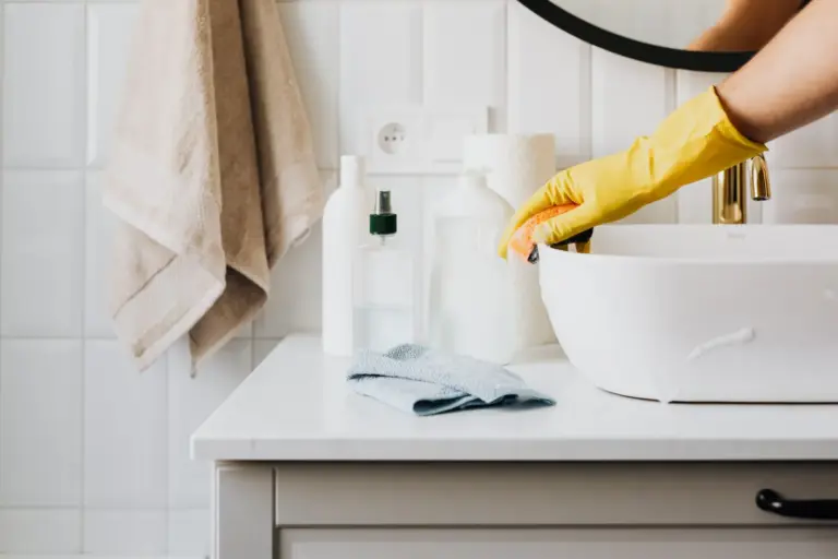 Gloved hand scrubbing a bathroom sink