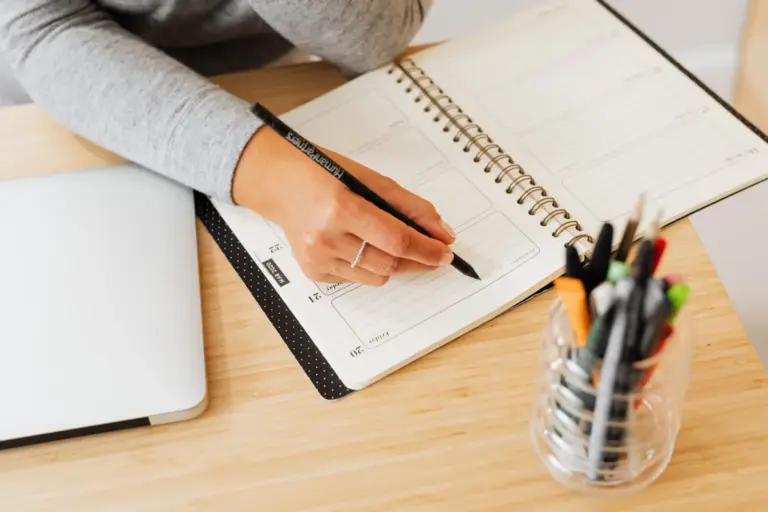Hand writing in a weekly planner on a wooden desk