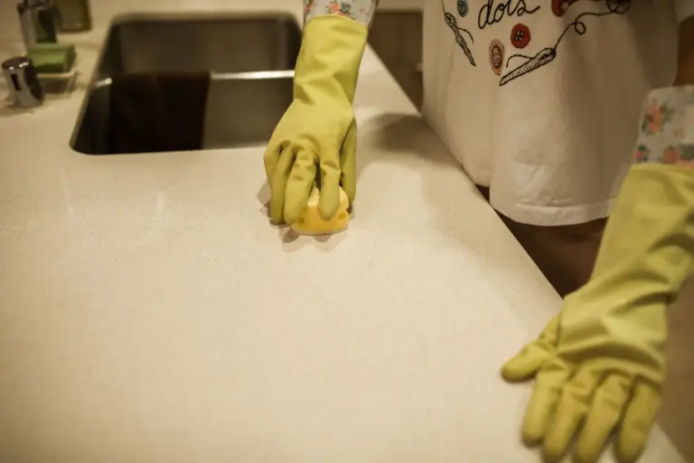 Gloved hands wiping a kitchen counter with a cloth