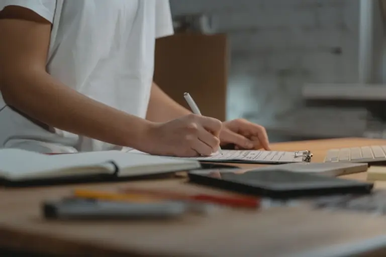 Hands writing notes on a clipboard at a desk